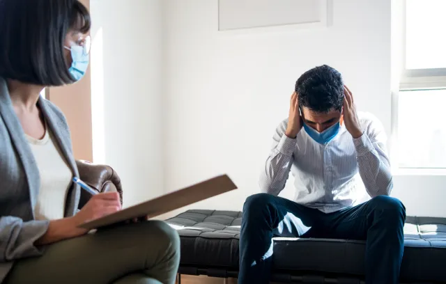 Foto de una persona agarrandose la cabeza en un consultorio