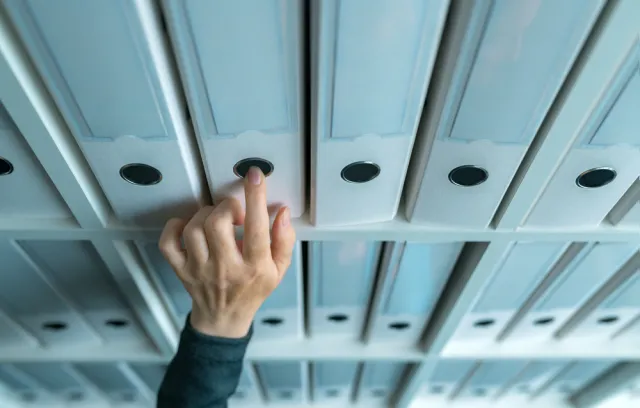 Foto de una persona buscando unos folders en una carpeta de negocios