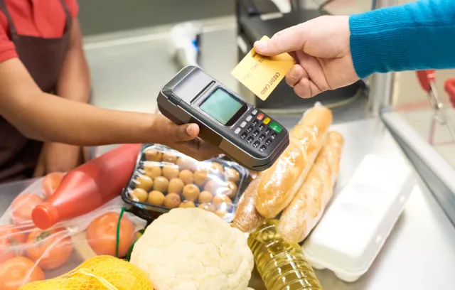 Foto de una persona comprando con una tarjeta mediante un datafono