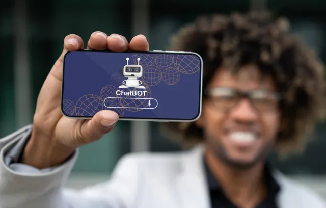 Foto de una persona con un celular en la mano que dice chatbot
