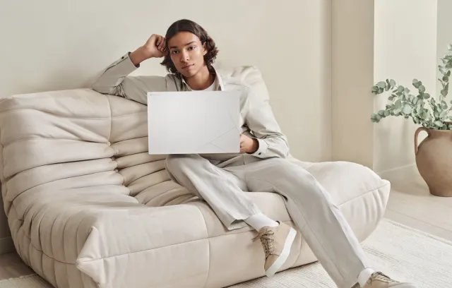 Foto de una persona con una computadora asus blanca sobre un sofa