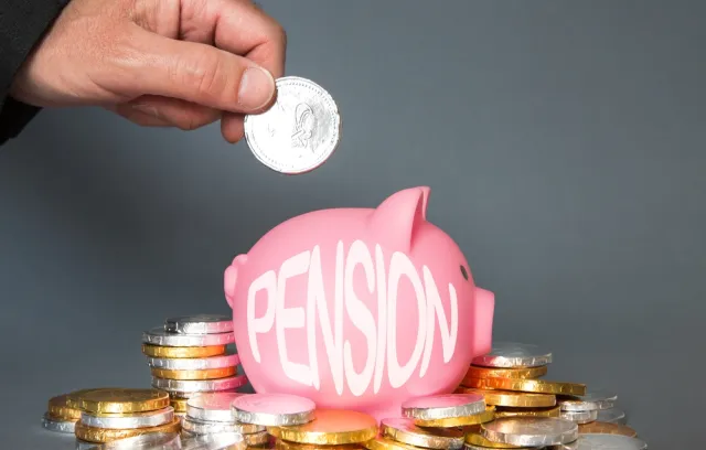 Foto de una persona depositando una moneda en un marrano rosado