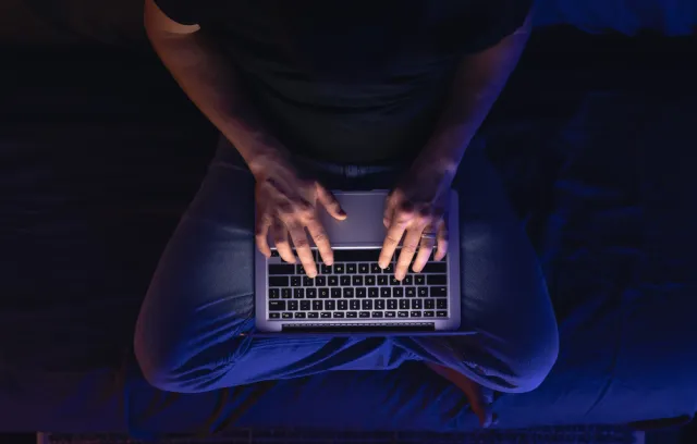 Foto de una persona escribiendo sobre un computador sobre las piernas