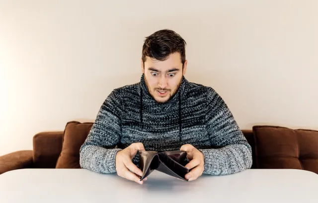 Foto de una persona jóven mirando consternado la billetera