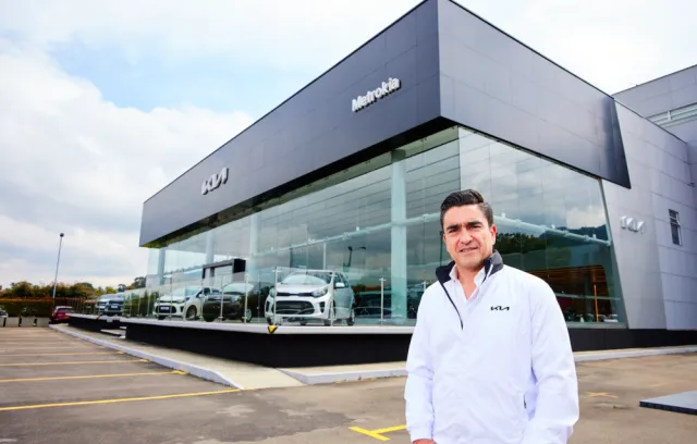 Foto de una persona posando frente a la cámara con un local detrás