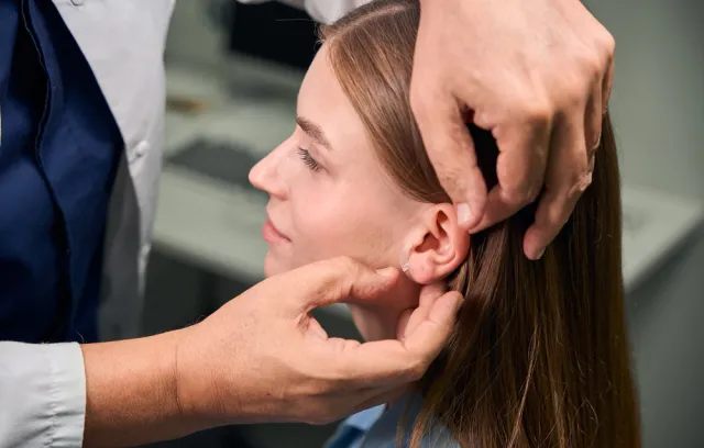 Foto de una persona revisando la oreja de una mujer