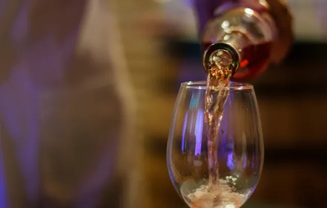 Foto de una persona sirviendo una copa de vino