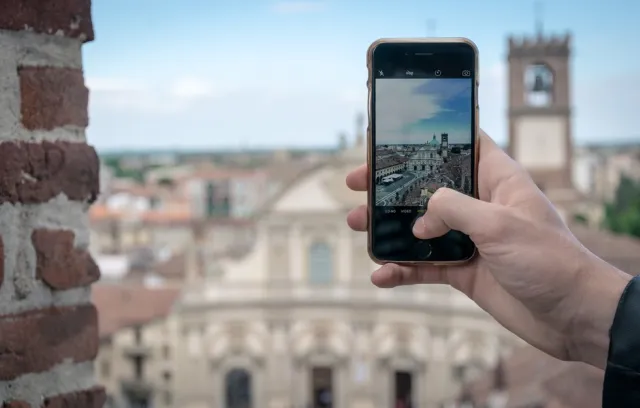 Foto de una persona tomando una fotografia con el celular y el fondo de una ciudad europea
