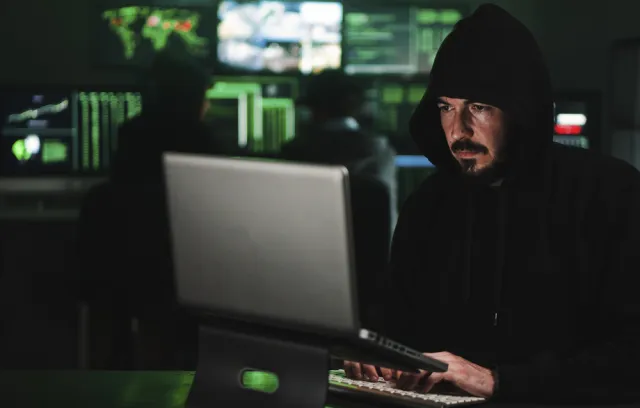 Foto de una persona trabajando con un hoodie frente a un computador