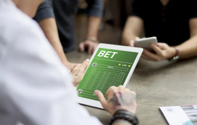 Foto de una persona utilizando una tablet con una plataforma de apuesta en la pantalla