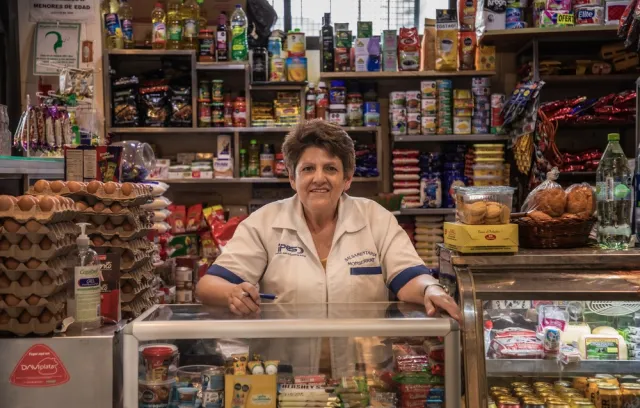 Foto de una señora frente a unos stands de una tienda de barrio