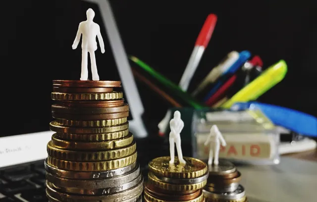 Foto de unas personas sobre monedas de oro en un escritorio