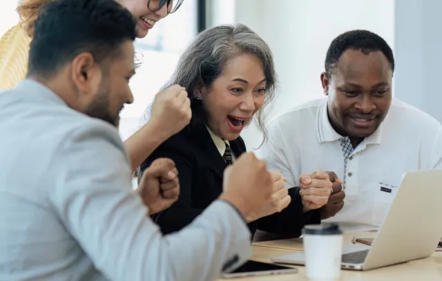 Foto de varias personas reunidas celebrando frente al computador