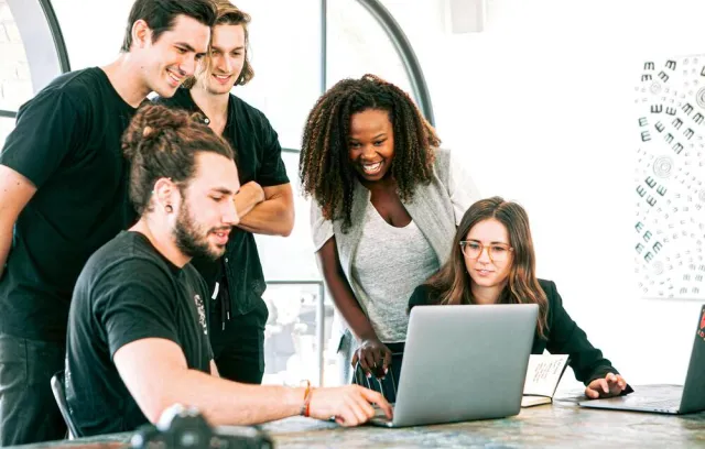 Foto de varias personas reunidas frente a un computador