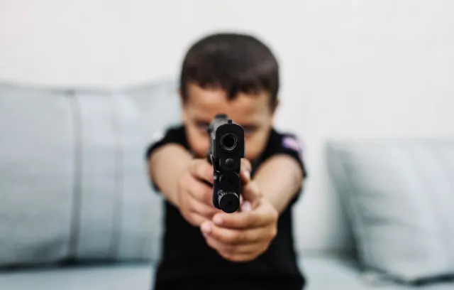 Foto ilustrativa de un niño con un arma