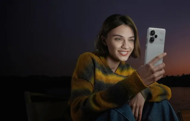 Fotografia de una mujer revisando un celular gris con un atarceder de fondo