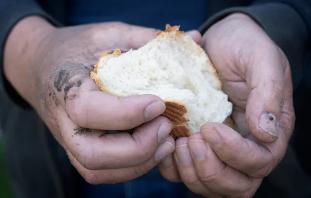 Imagen de una persona con un pan en la mano.