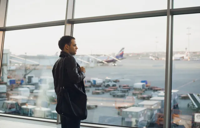 Hombre con traje negro mirando por la ventan de un aeropuerto