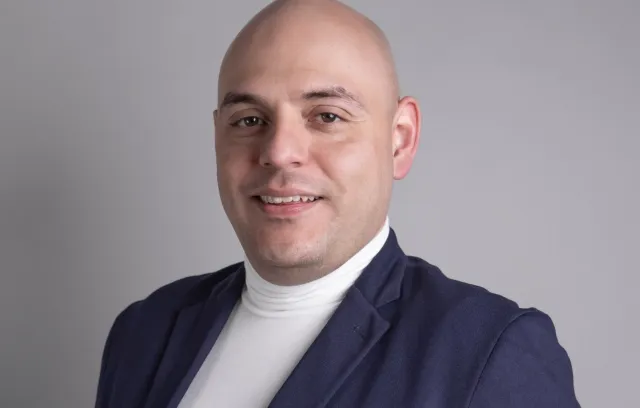 Hombre mirando a la cámara con blazer azul y camiseta blanca
