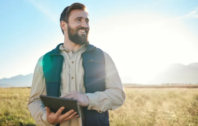 Hombre mirando el horizonte hacía la cámara con un paisaje rural