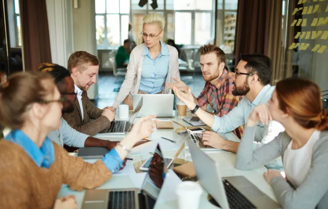 Hombres y mujeres en una mesa compartiendo ideas