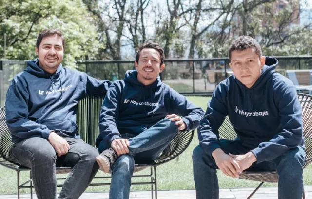 Tres jóvenes sentados, sonriendo a la cámara