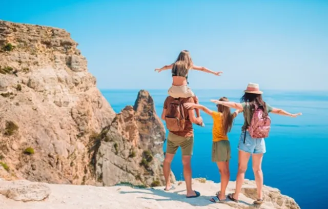 Imagen de una familia mirando al mar con un sol a sus espaldas