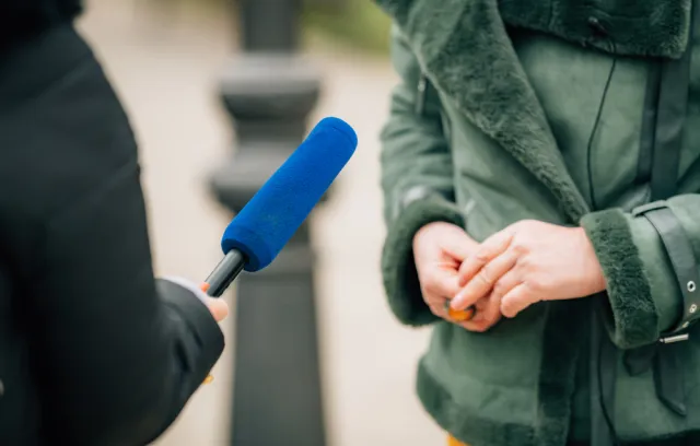 Foto de una persona con un micrófono azul entrevistando