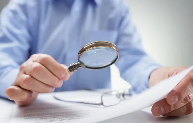foto de una persona leyendo un documento con lupa