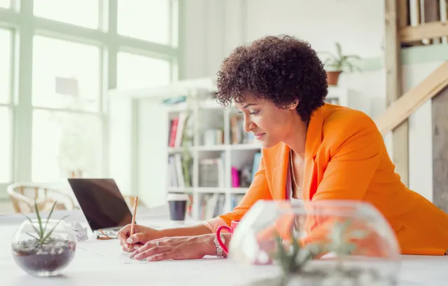 Mujer con blazer naranja mirando el computador