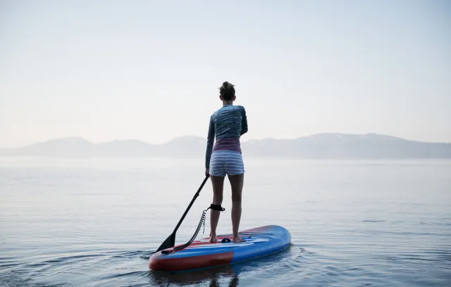Mujer encima de una tabla en un lago