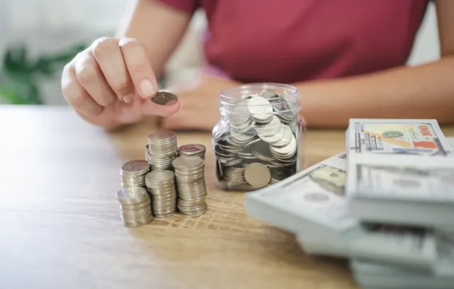 Persona recopilando monedas y billetes sobre una mesa