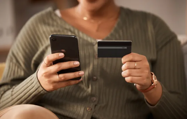 Persona sosteniendo una tarjeta en una mano y un celular en la otra
