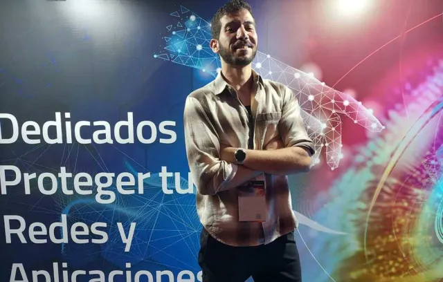 Foto de una persona cruzada de brazos con un fondo que dice dedicados a proteger tus redes y aplicaciones