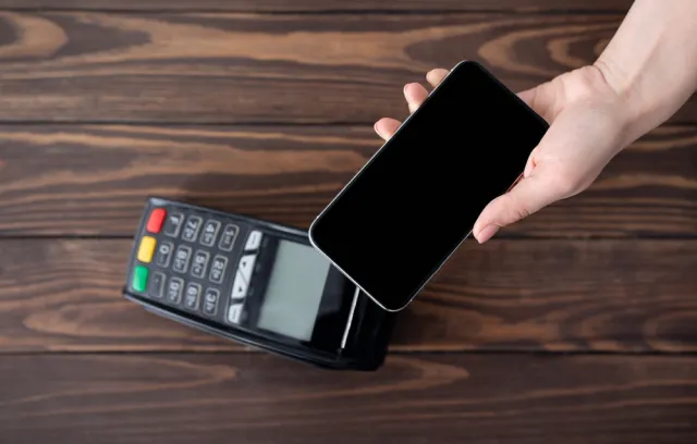 Representación de un datáfono con un celular encima, simulando un pago en línea