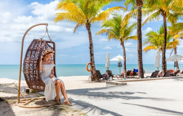 Mujer ubicada en una silla de playa con palmeras al fondo