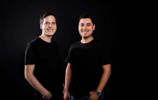Foto de dos hombres con camiseta negra sonriendo a la cámara