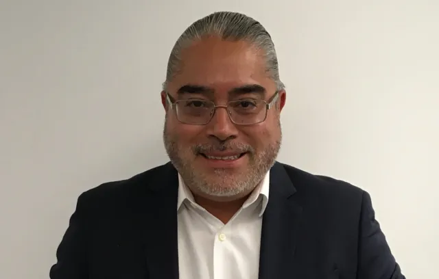 Foto de un señor con gafas blancas, mirando a la cámara con pelo hacía a trás