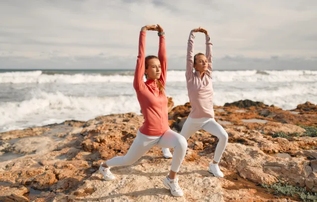 Dos mujeres haciendo deportes con la playa de fondo