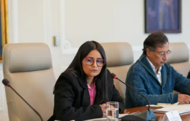 Foto de una mujer con sentada con un micrófono al frente