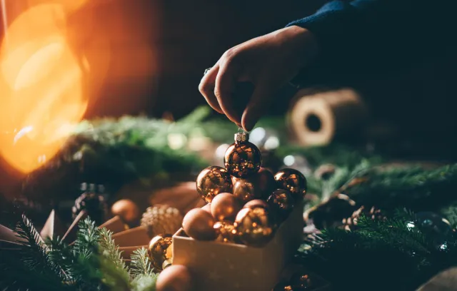 Foto de una foto de navidad, de una persona poniendo una bola de navidad en un canasto
