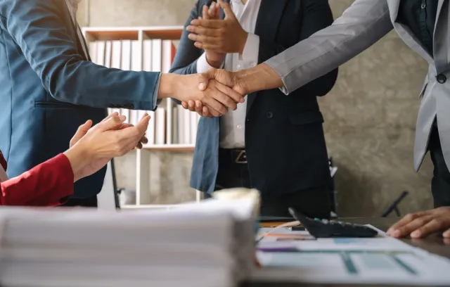 Foto de dos personas dándose la mano sobre una mesa