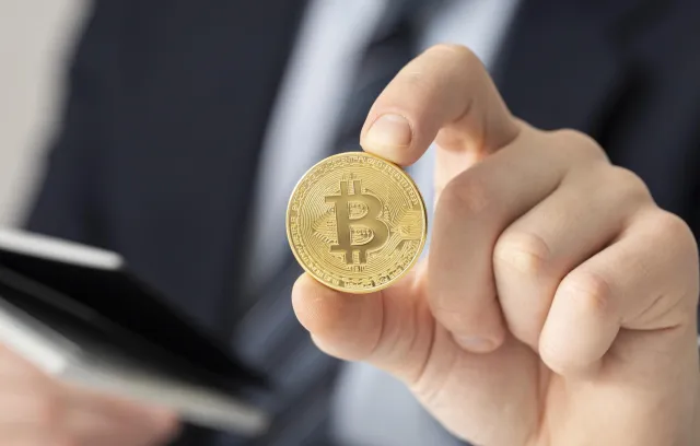 Foto de una personas sosteniendo una moneda con el logo de las cripto