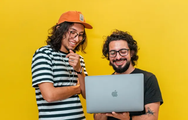 foto de dos personas mirando un pc con fondo amarillo