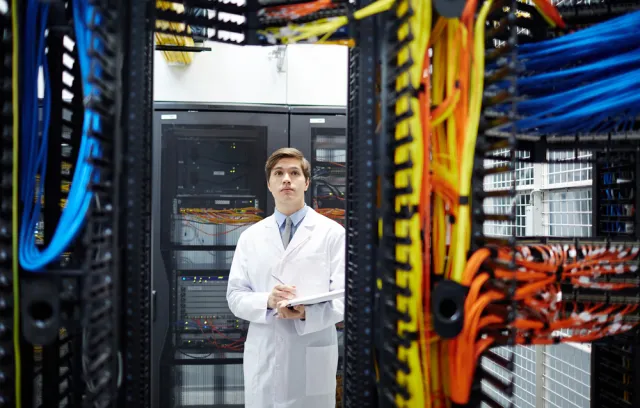 foto de un señor con bata frente a un computador grande