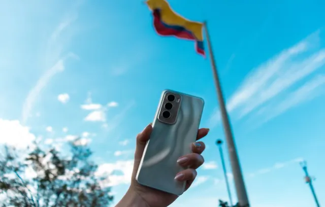 foto de una mano sosteniendo un celular con una bandera de fondo