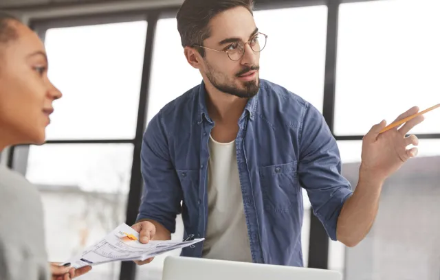 Hombre explicando un concepto a una colega en el trabajo