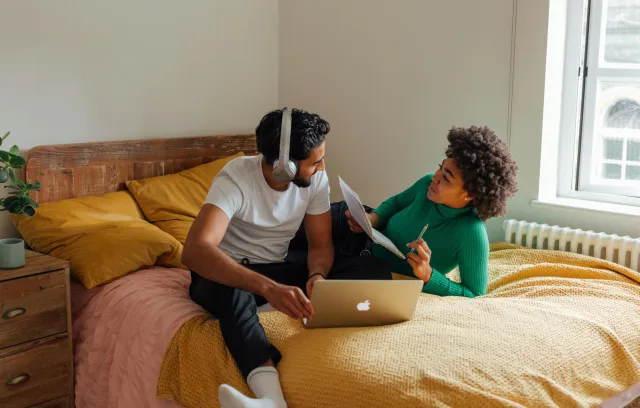 Dos personas en cama con una laptop