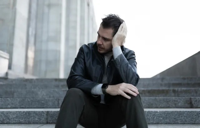 Foto de un hombre sobre una escalera aburrido mirando hacía un costado