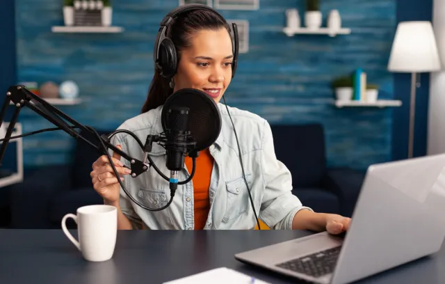 Foto de mujer hablando por micrófono al frente de un computador